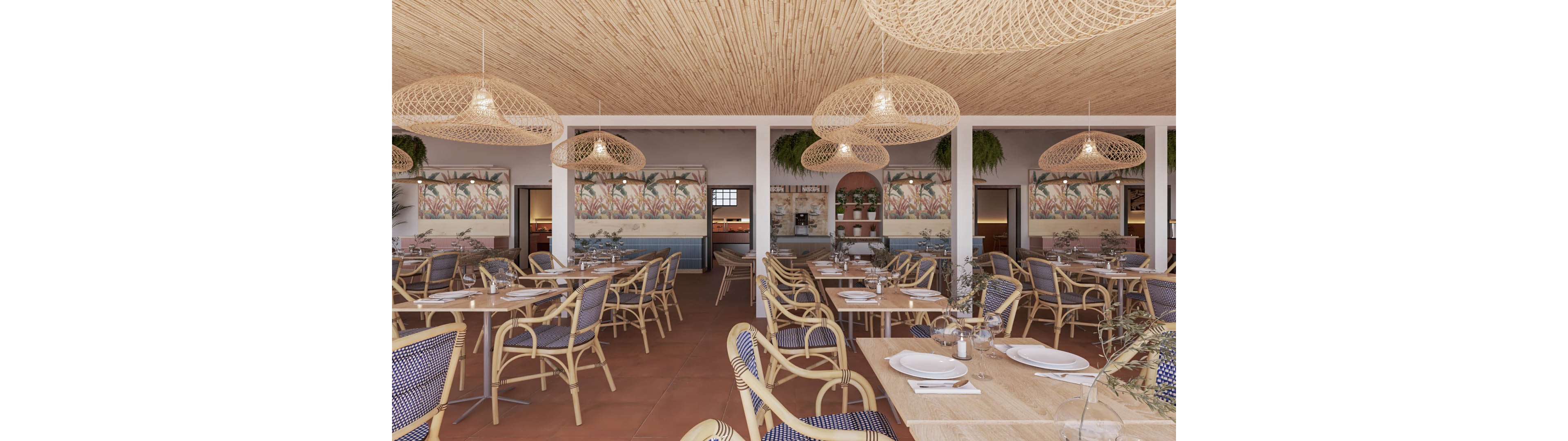 Spacious restaurant interior featuring woven rattan chairs and light wooden tables neatly set with white plates and glassware. The space has a warm, coastal aesthetic with terracotta flooring and a bamboo-style ceiling. Large wicker pendant lights hang overhead, casting a soft glow across the dining area. Colorful wall murals and hanging plants add decorative detail to the relaxed, airy atmosphere.