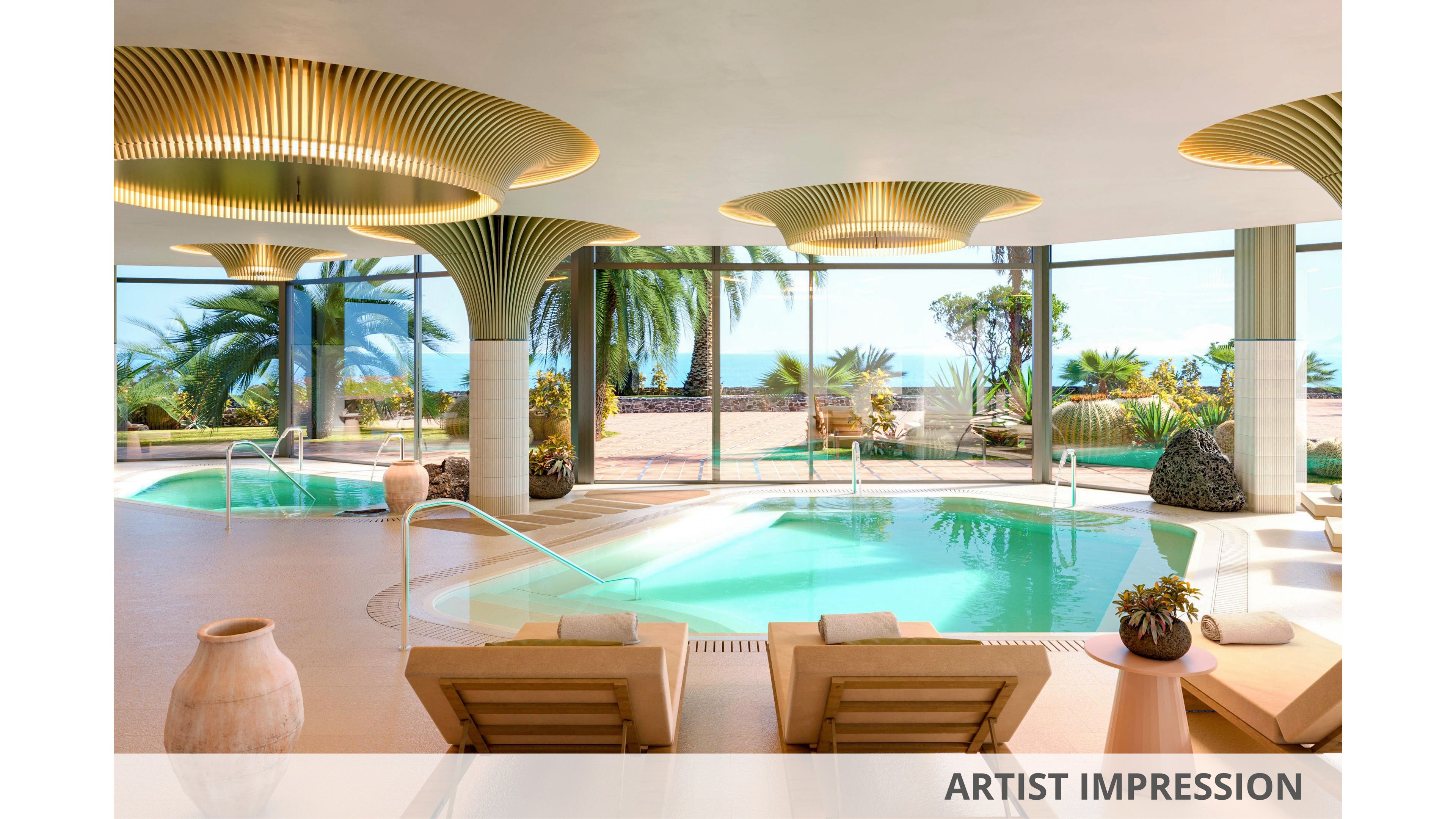 Artist impression of a luxurious indoor spa pool overlooking a tropical beachfront. Curved loungers face the turquoise water, framed by large floor-to-ceiling windows. Sculptural golden ceiling lights and potted plants add an elegant, contemporary atmosphere. Palm trees and the distant sea create a serene, resort-style setting.