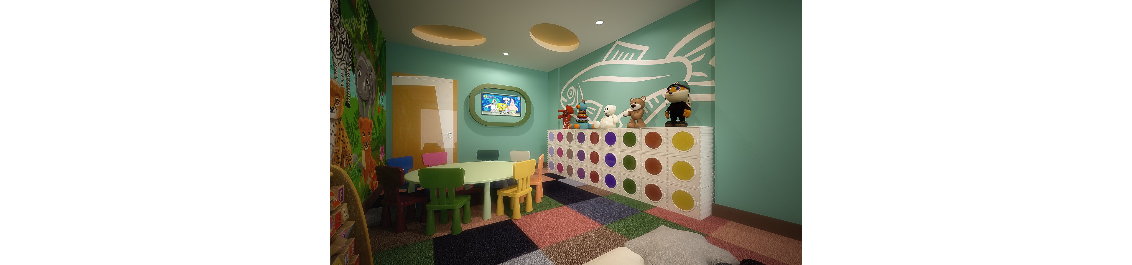 A brightly colored children's playroom features a small round table surrounded by multicolored chairs. A wall-mounted television displays a cartoon above a low cabinet with large circular color accents. Plush toys are arranged on top of the cabinet, and the walls are painted with playful murals and a large fish outline. The floor is covered with a patchwork of soft, multicolored carpet tiles, creating a cozy and inviting space for kids.