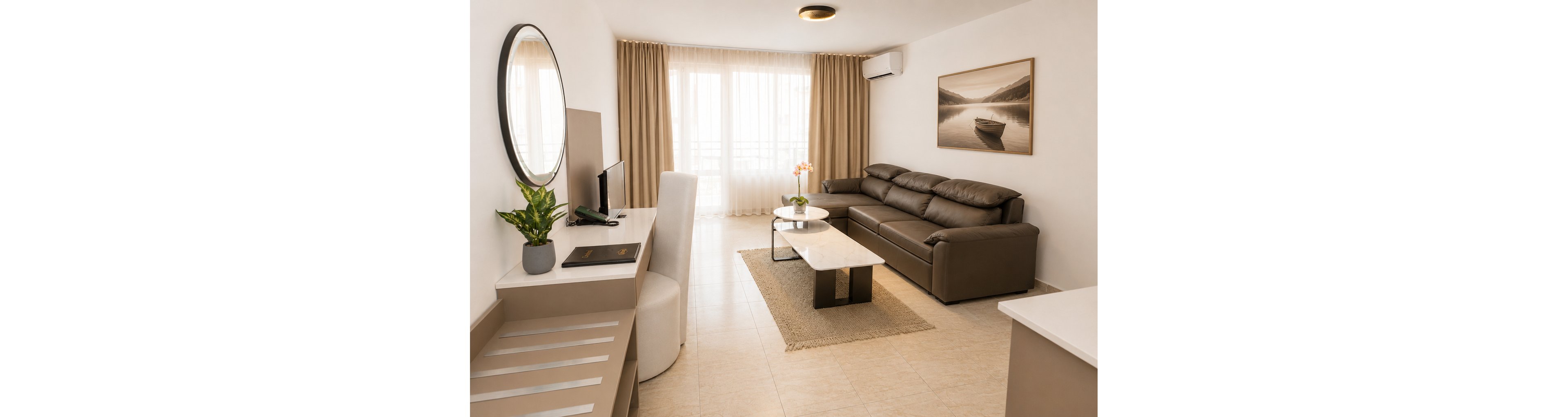 Contemporary living room interior featuring a large brown leather sofa and a sleek white coffee table. The space is brightened by floor-to-ceiling windows with beige curtains allowing natural light to fill the room. A wall-mounted television, desk area, and indoor plants add functionality and decor. A framed boat landscape artwork and neutral color palette create a calm, minimalist atmosphere.