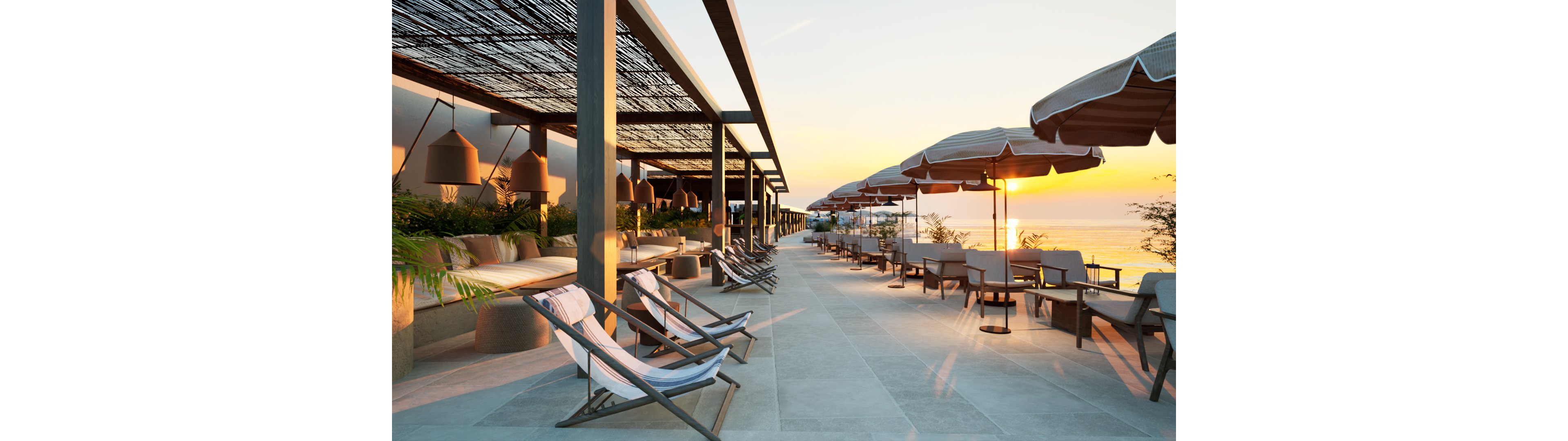 A contemporary outdoor terrace overlooks the ocean at sunset, featuring rows of reclining sun loungers and shaded seating areas. Large umbrellas and pergola structures with woven canopies create a relaxed, resort-style atmosphere. Soft seating, hanging lamps, and potted greenery add comfort and warmth to the minimalist design. The golden light of the setting sun reflects off the water, enhancing the tranquil coastal setting.