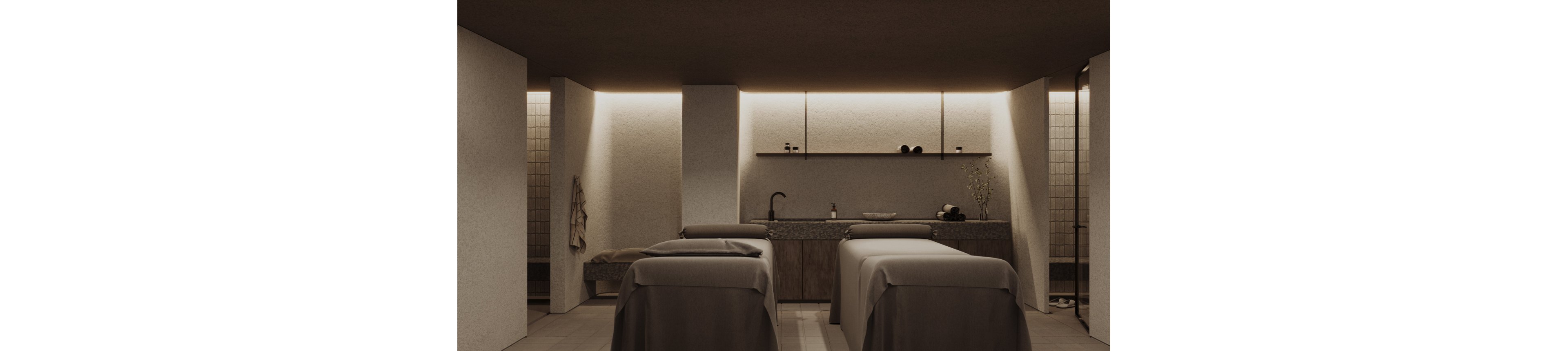 A modern spa treatment room features two massage tables covered in neutral-toned linens. The space has a minimalist design with soft, indirect lighting along the back wall. A countertop with a sink, shelves, and small decor items runs across the rear of the room. Warm earthy colors and simple lines create a calm, relaxing atmosphere.