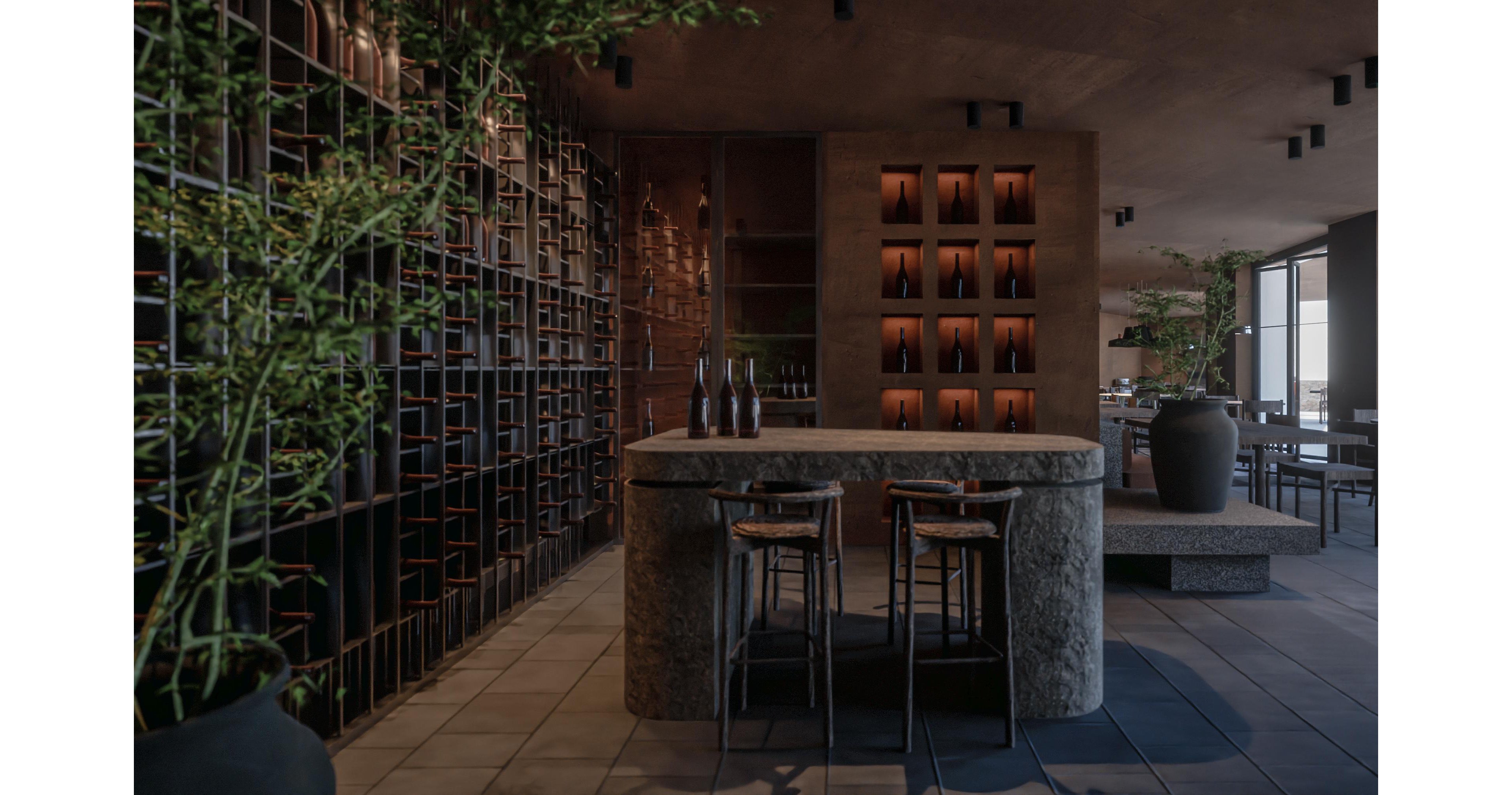 A contemporary wine bar interior features a central stone counter with two stools in a dimly lit space. Wine bottles are displayed on wall-mounted racks and in a backlit niche behind the counter. Large planters with green plants soften the industrial design and add natural accents. The overall atmosphere is warm and sophisticated, with dark tones and subtle lighting creating an intimate setting.