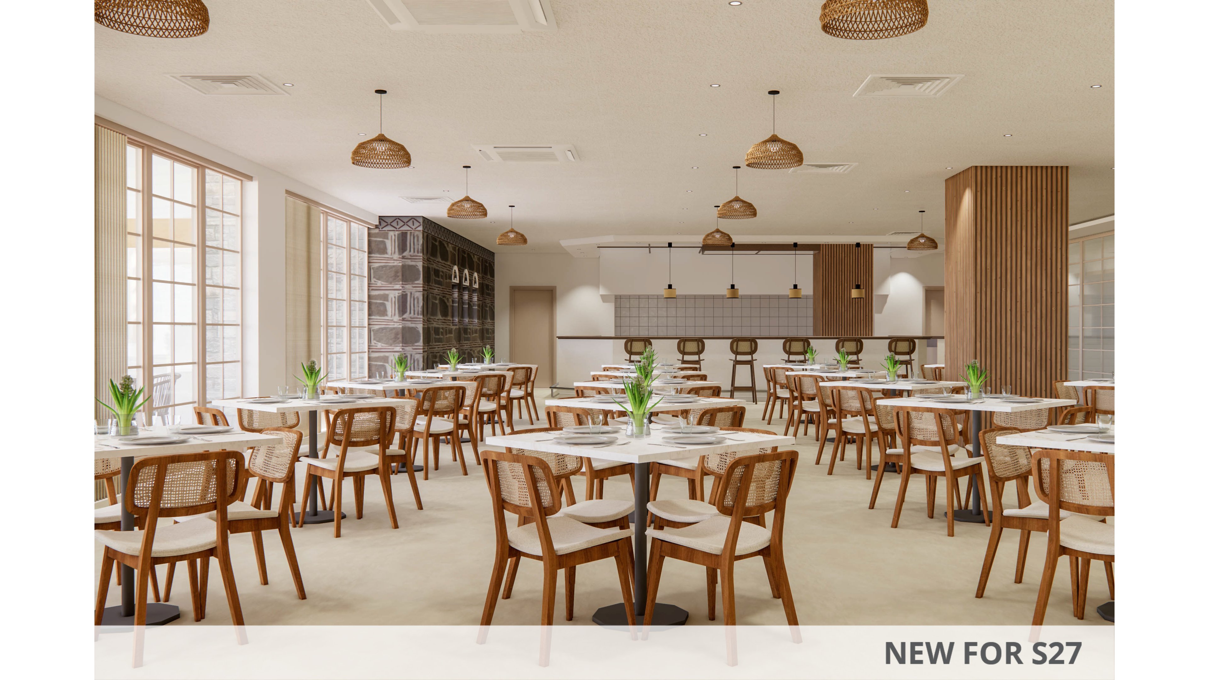 Spacious contemporary restaurant interior featuring multiple round tables and wooden chairs. The room is bright with large windows along one side allowing natural light to fill the space. A minimalist bar area with high stools is visible at the back, complemented by warm pendant lighting. Neutral tones, light wood finishes, and small green plants on each table create a calm, welcoming atmosphere.