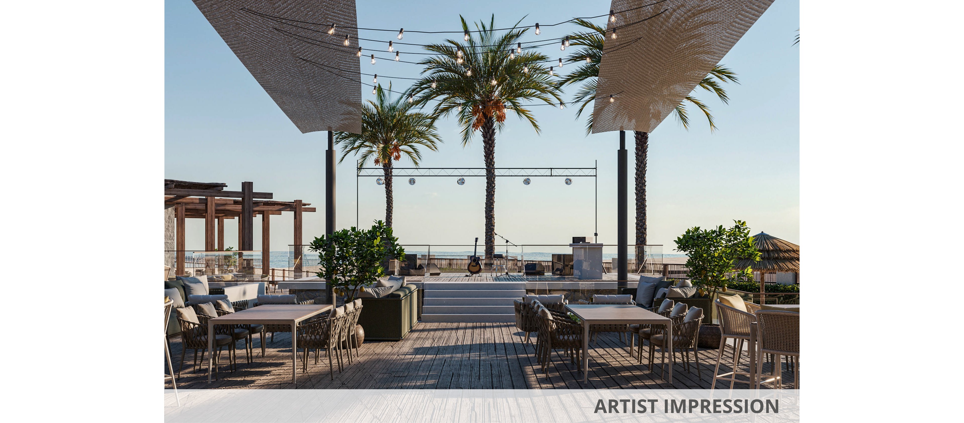 An open-air restaurant terrace overlooks a calm beachfront with palm trees and distant ocean views. Empty tables and chairs are arranged on a wooden deck, suggesting a relaxed dining or lounge area. String lights are suspended overhead, adding a warm and inviting ambiance. The scene feels tranquil and resort-like, ideal for evening gatherings by the sea.