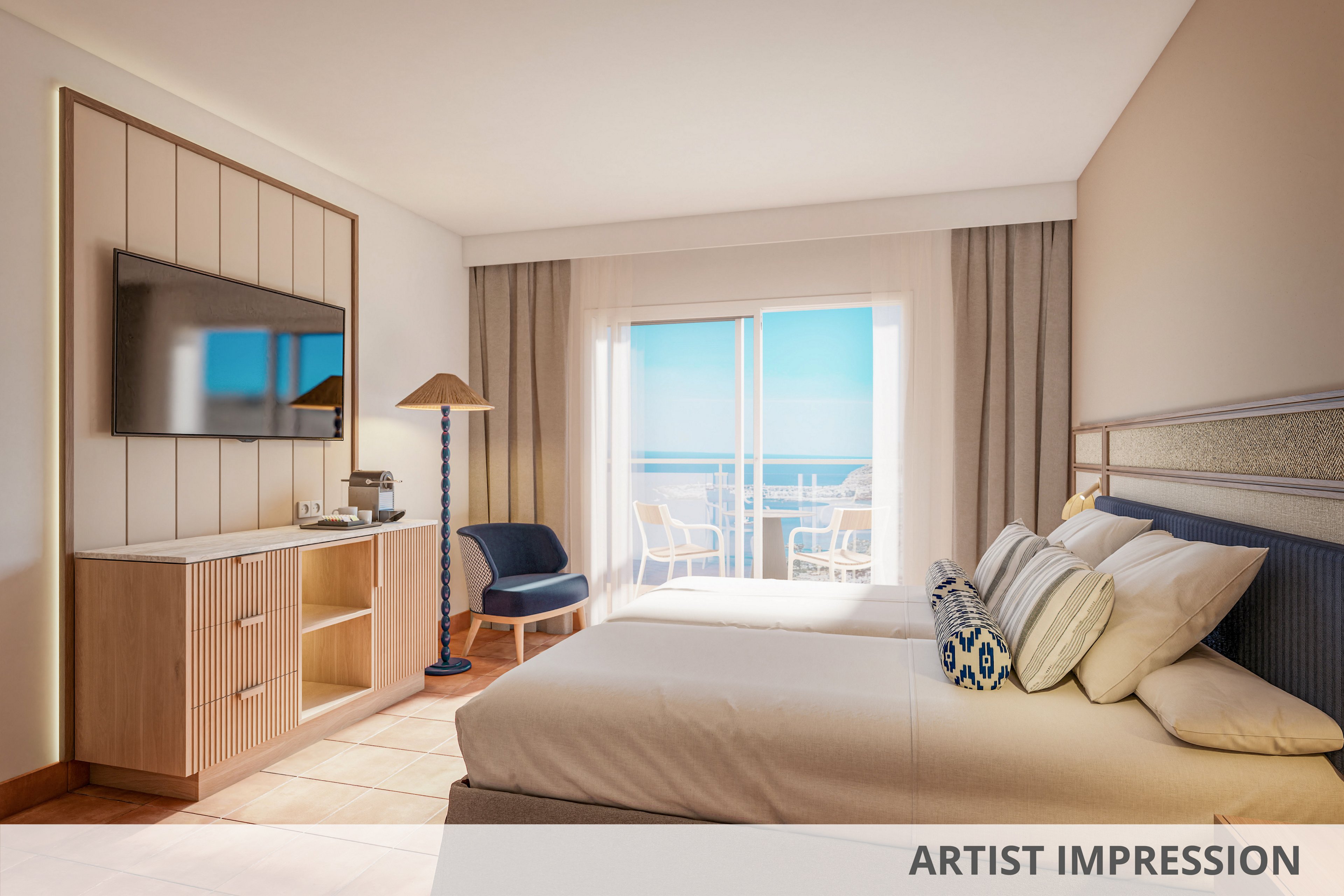 A modern hotel room features a neatly made double bed facing a wall-mounted flat-screen TV and light wood cabinetry. Large glass doors open onto a balcony with white chairs and a table, overlooking a clear blue ocean and sky. Neutral tones of beige and cream are accented by blue decor elements, including a patterned cushion and chair. Soft natural light fills the space, creating a calm and inviting atmosphere for guests.