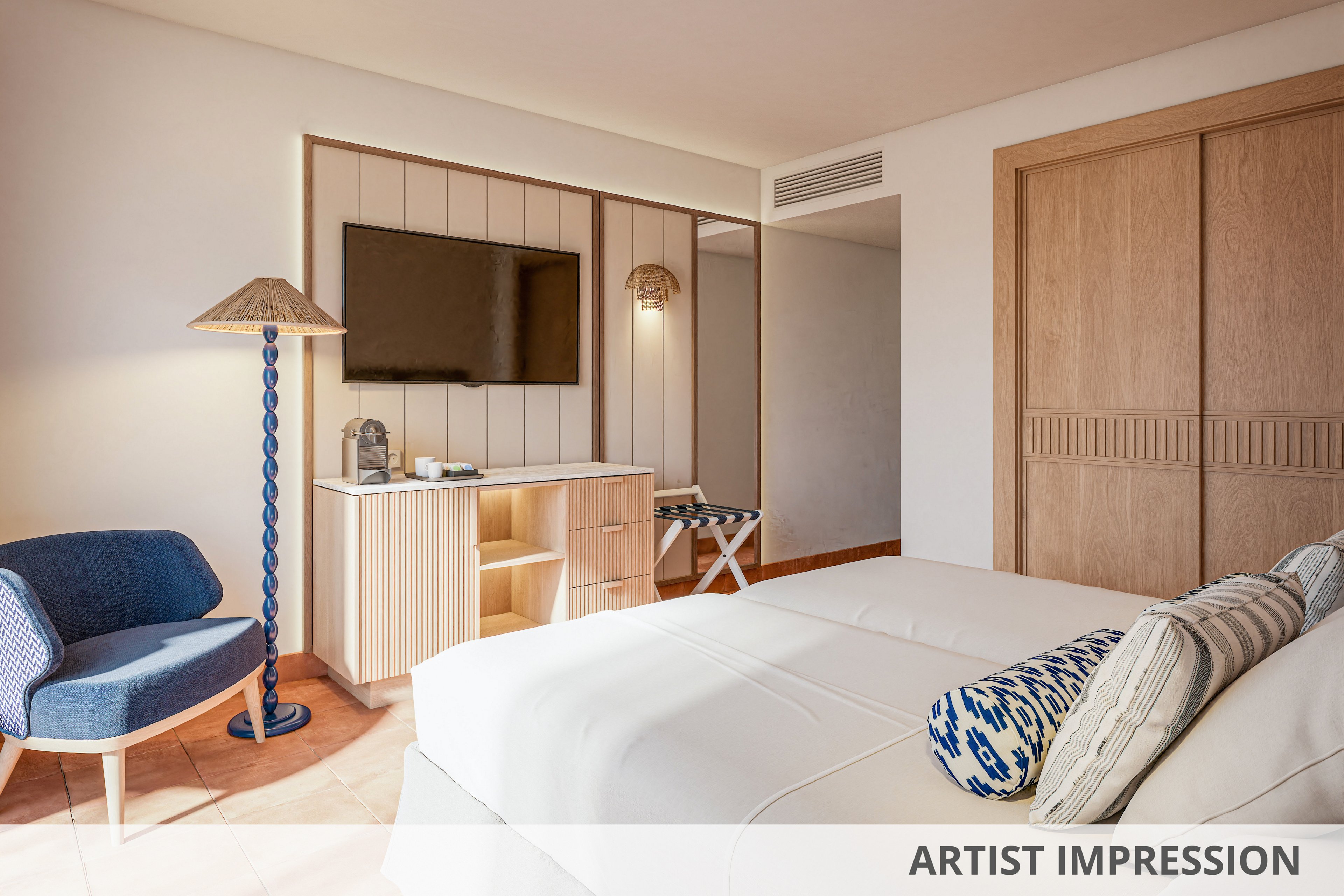 A contemporary hotel room features two neatly made beds with patterned accent pillows. A flat-screen television is mounted above a light wood console that holds decorative items and a small lamp. A blue upholstered chair and floor lamp add color to the neutral interior, while large wooden sliding doors conceal storage space. Soft natural light enhances the clean, minimalist design and relaxed atmosphere.