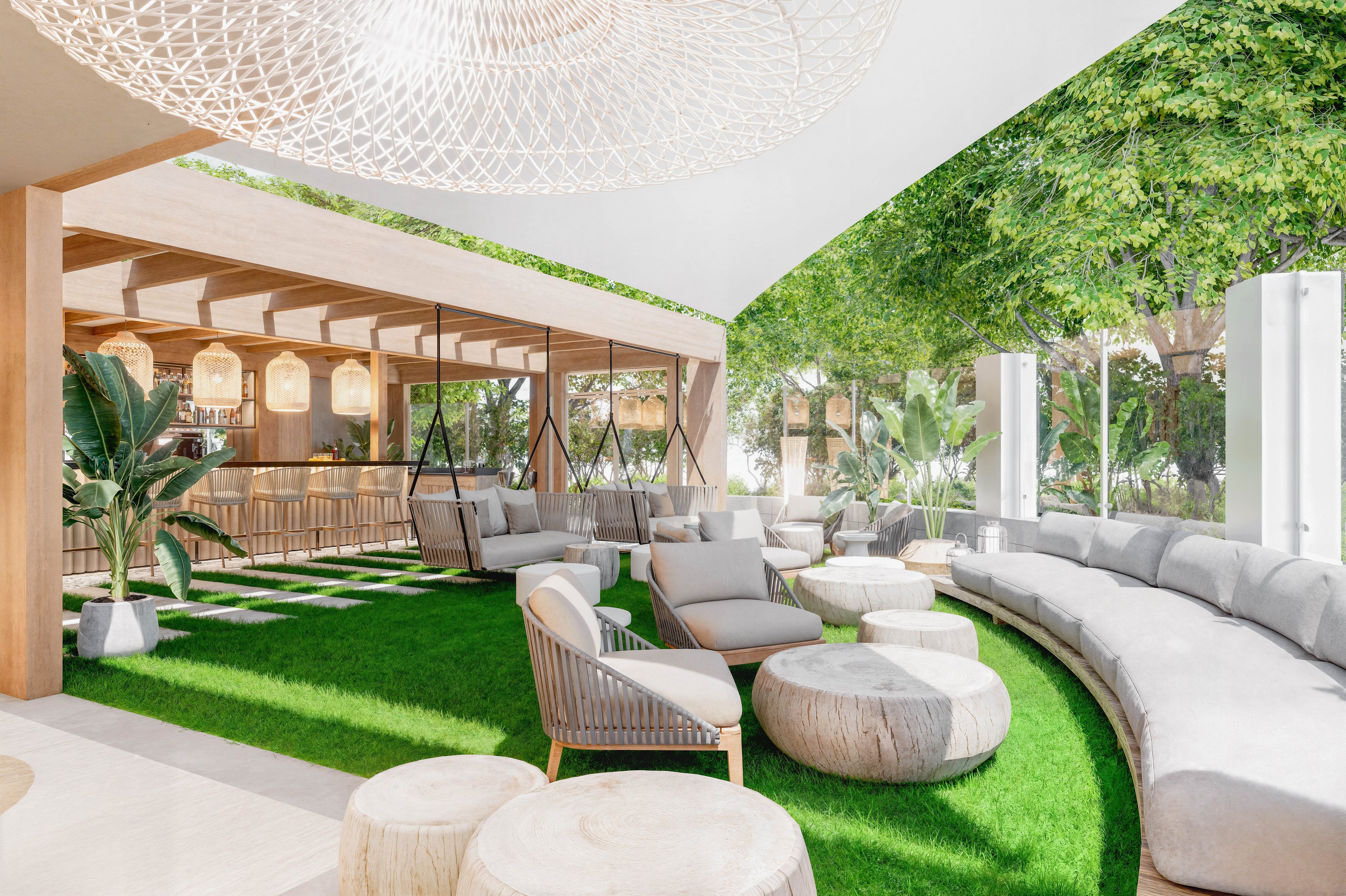 A contemporary open-air lounge features a large curved sofa surrounding a grassy seating area. Neutral-toned armchairs and round ottomans are arranged on artificial turf beneath a light, airy canopy. Wooden beams, woven light fixtures, and potted tropical plants create a natural, resort-like atmosphere. Large windows and abundant greenery blur the boundary between indoor and outdoor space, suggesting a relaxed social setting.
