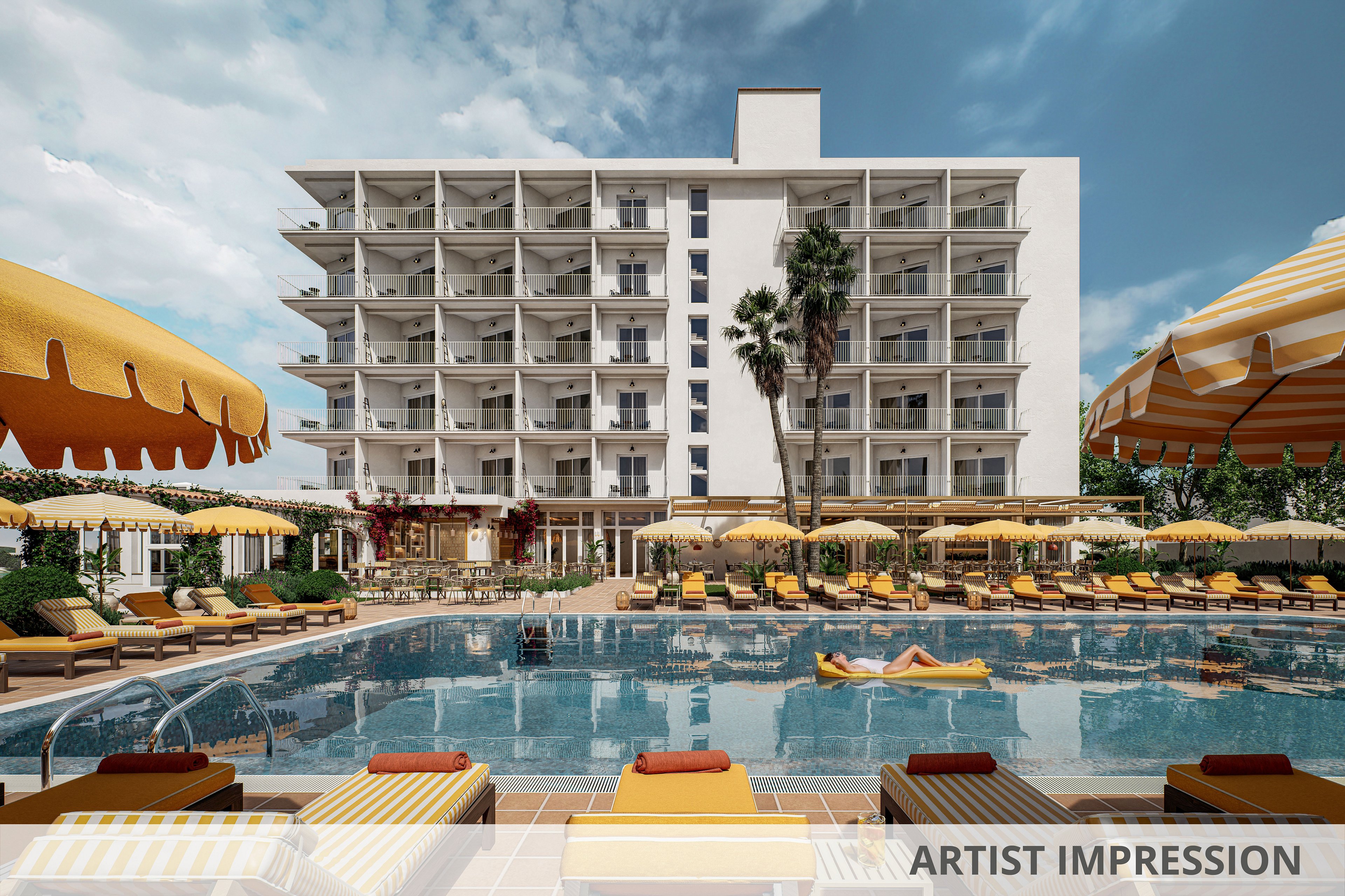 A large outdoor swimming pool sits in front of a multi-story resort hotel with balconies on each floor. Yellow-and-white striped umbrellas and cushioned sun loungers surround the pool, where a few guests relax on chairs and inflatables. Tall palm trees and landscaped greenery add a tropical feel to the scene. The sky is partly cloudy, creating a bright yet soft vacation atmosphere.