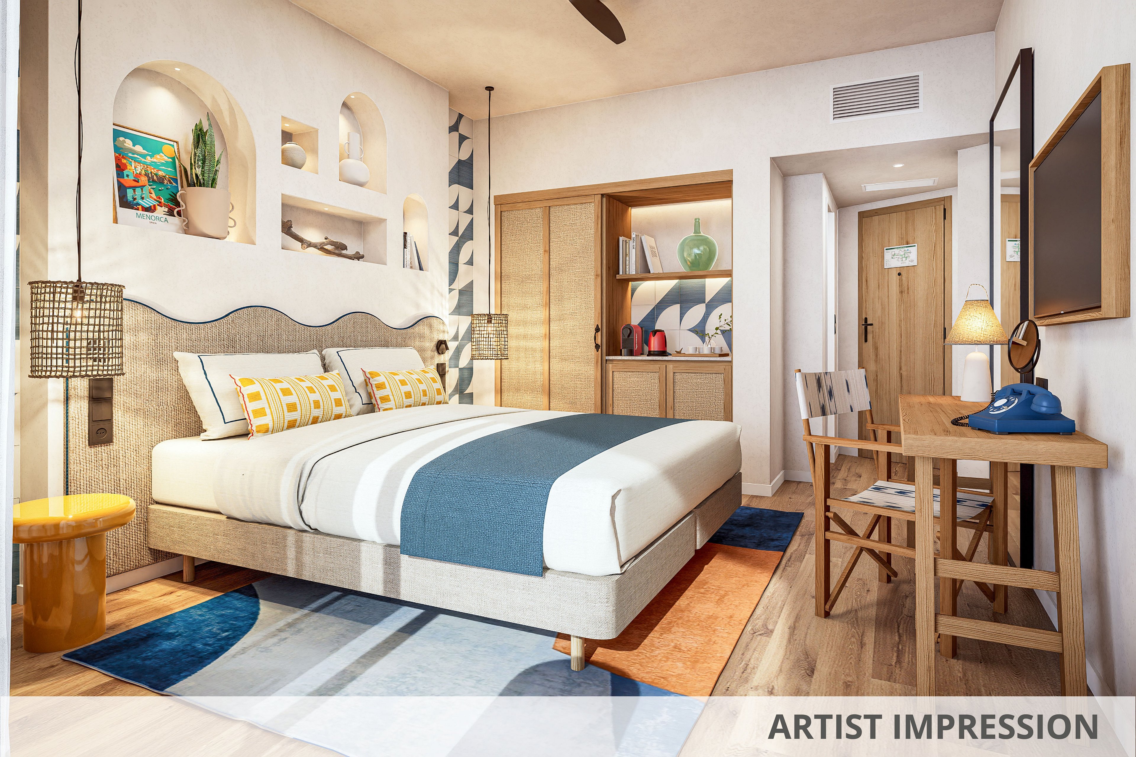 A contemporary hotel bedroom features a neatly made double bed with blue and white bedding and patterned pillows. Built-in wall niches display decorative objects and books, while warm pendant lights frame the headboard. A wooden desk with a chair and retro-style telephone sits opposite the bed, next to a door with a hanging sign. The room is accented by a colorful rug, coastal artwork, and soft neutral walls, creating a welcoming vacation atmosphere.