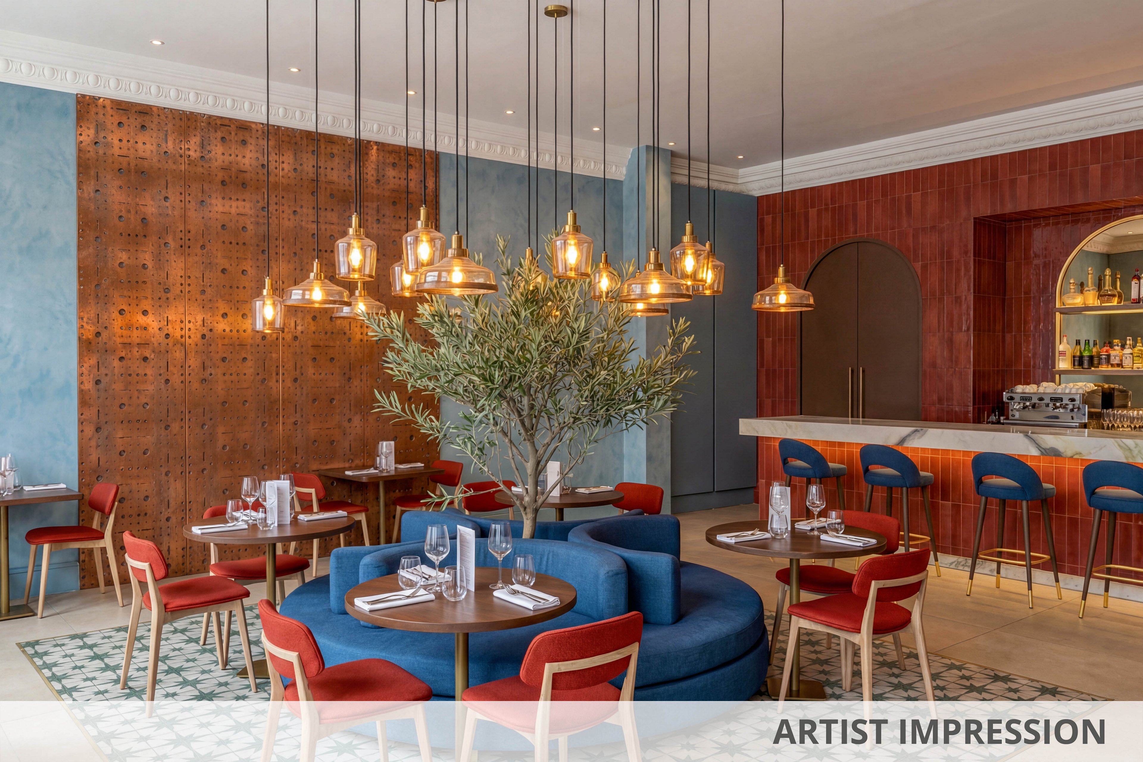 A stylish restaurant features a central blue circular sofa surrounded by red chairs and wooden tables. Warm pendant lighting hangs above, illuminating a patterned tile floor and a decorative indoor tree. The bar area in the background showcases a variety of bottles and glassware, with a mix of blue and gold accents. The walls display a combination of textured blue and copper tones, creating a contemporary and inviting atmosphere. No visible text or numbers are present in the image.