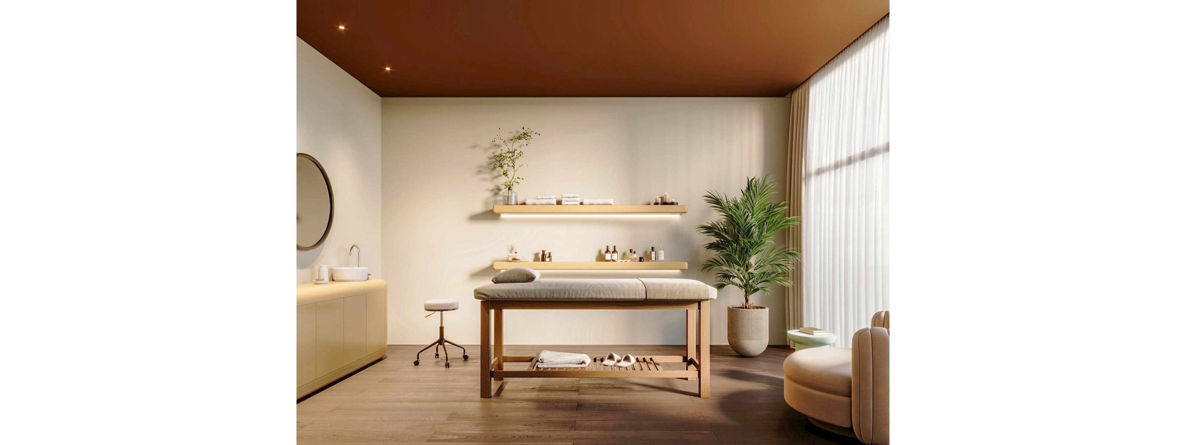 A contemporary spa treatment room features a wooden massage table with neatly folded towels and accessories beneath. Soft neutral walls, floating shelves with small bottles, and a round mirror over a sink create a clean, organized setting. Warm lighting and a large potted plant add natural elements and a calming atmosphere. Floor-to-ceiling sheer curtains diffuse daylight, enhancing the serene, minimalist design.