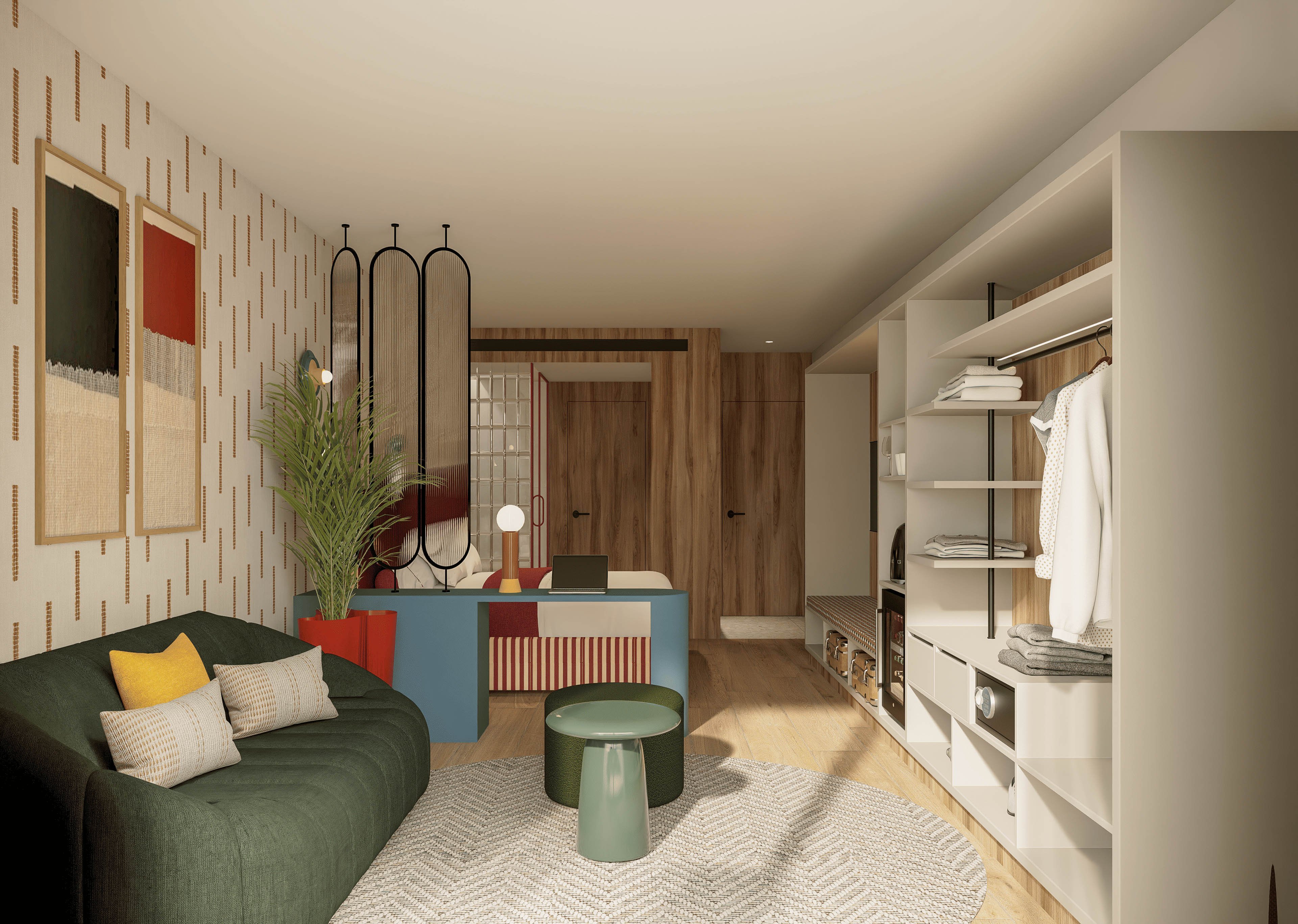 Contemporary studio apartment features a cozy seating area with a dark green sofa and layered cushions. An open wardrobe with neatly arranged clothes and shelves lines one side of the room. The space includes a small round green table, a textured rug, and warm wooden finishes throughout. Abstract wall art and decorative screens add visual interest, creating a stylish and inviting atmosphere.