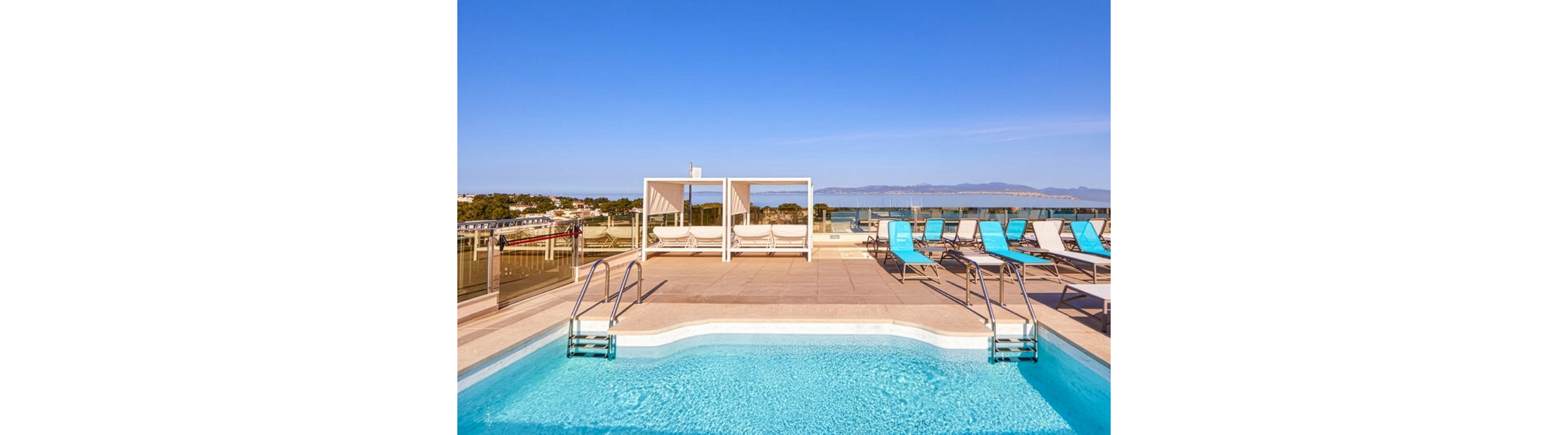 A contemporary rooftop swimming pool is featured under a clear blue sky, surrounded by stylish lounge chairs and a white canopy bed. The pool area overlooks a scenic cityscape and distant mountains, creating a relaxing and luxurious atmosphere. The setting is bright and inviting, with clean lines and a tranquil vibe. No visible people or text are present in the image.