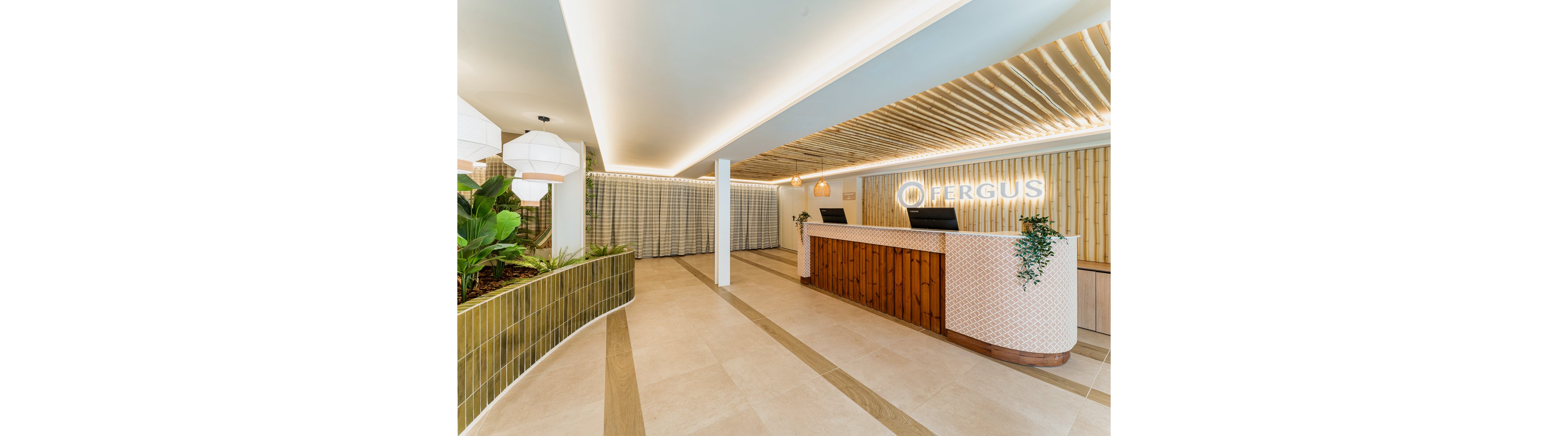 The image shows a contemporary hotel reception area with the unmistakable 'FERGUS' logo illuminated on the wall behind the desk. The setting features a spacious lobby with wood and tile accents, lush indoor plants, and geometric lighting fixtures. The mood is welcoming and fresh, with a neutral palette and clean lines. No people are present, highlighting the architectural and interior design elements.