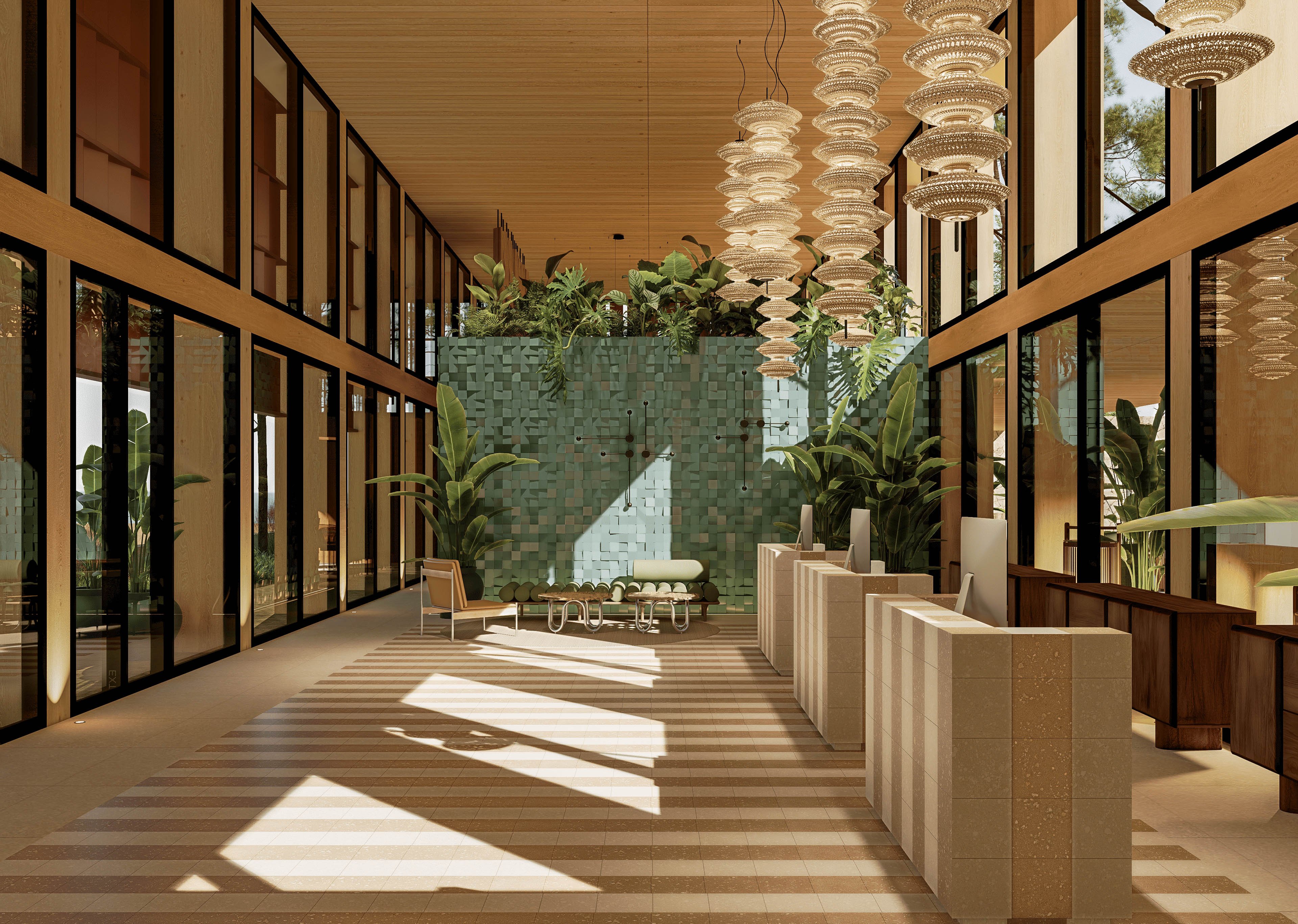 A spacious contemporary lobby features multiple light-colored reception desks aligned along the right side. Large floor-to-ceiling windows on the left flood the interior with natural light and views of greenery outside. A textured green tile wall and lush indoor plants create a tropical atmosphere around a central seating area. Warm wood ceilings, patterned flooring, and sculptural pendant lights add a refined, resort-like aesthetic.