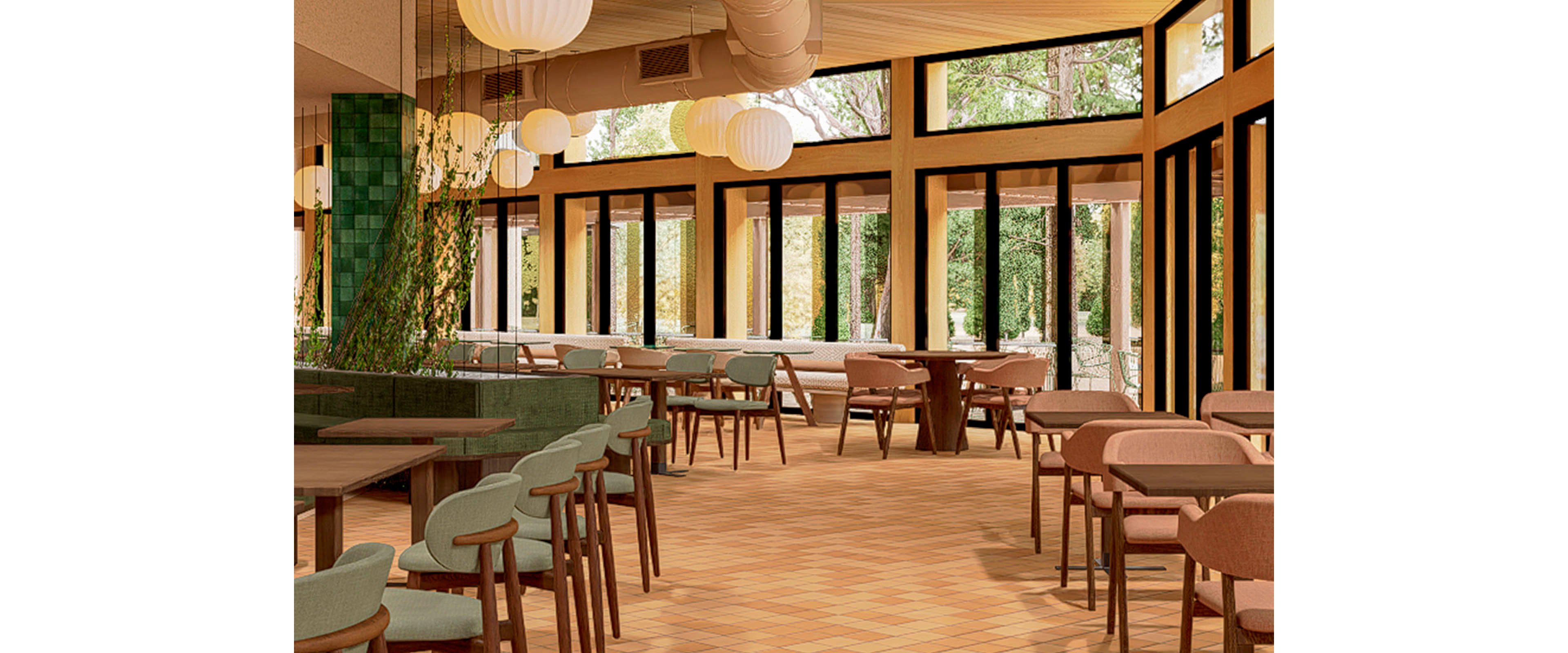 A contemporary restaurant interior features rows of wooden tables and upholstered chairs in soft green and muted pink tones. Large floor-to-ceiling windows line the space, allowing abundant natural light and views of lush greenery outside. Round pendant lights hang from the ceiling, adding warm ambient illumination. The overall design is clean and inviting, with a spacious layout and earthy color palette.