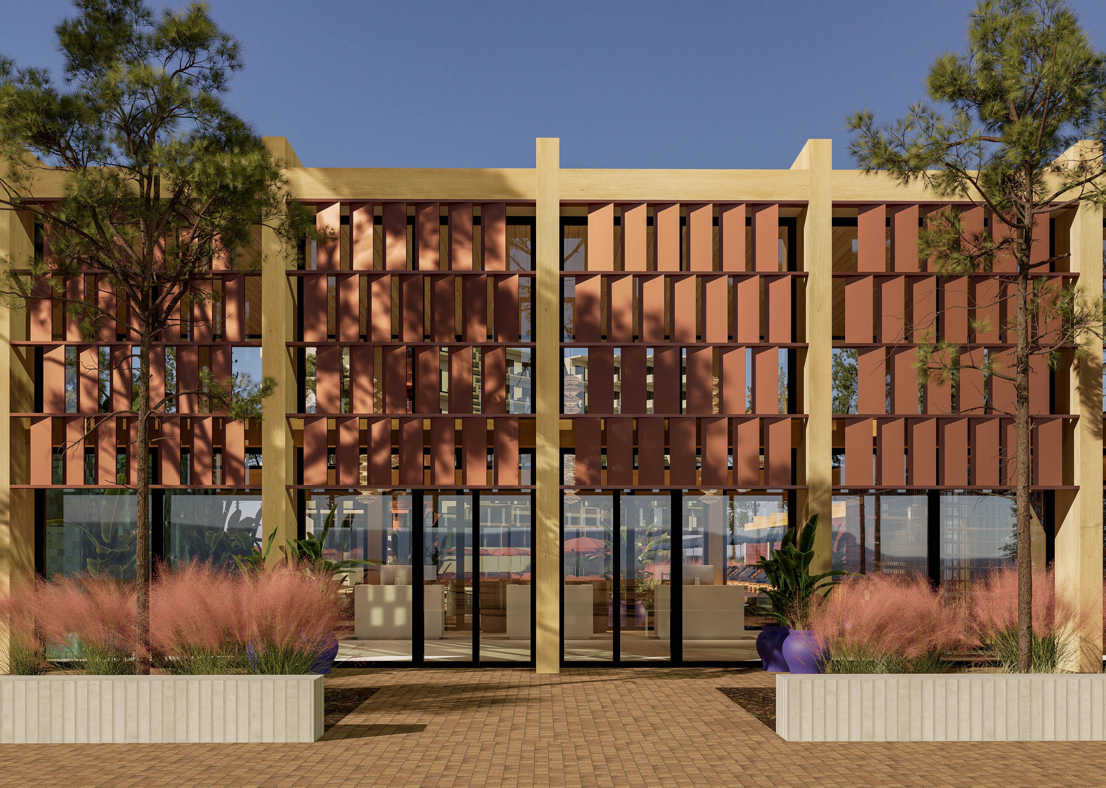 The image shows a contemporary building facade featuring vertical slatted panels in warm terracotta tones framed by light structural columns. Large glass doors and windows form the central entrance, reflecting the surrounding outdoor area. In front of the building, planters with ornamental grasses and potted greenery add texture and color. Tall trees and a clear blue sky complete the modern architectural setting.
