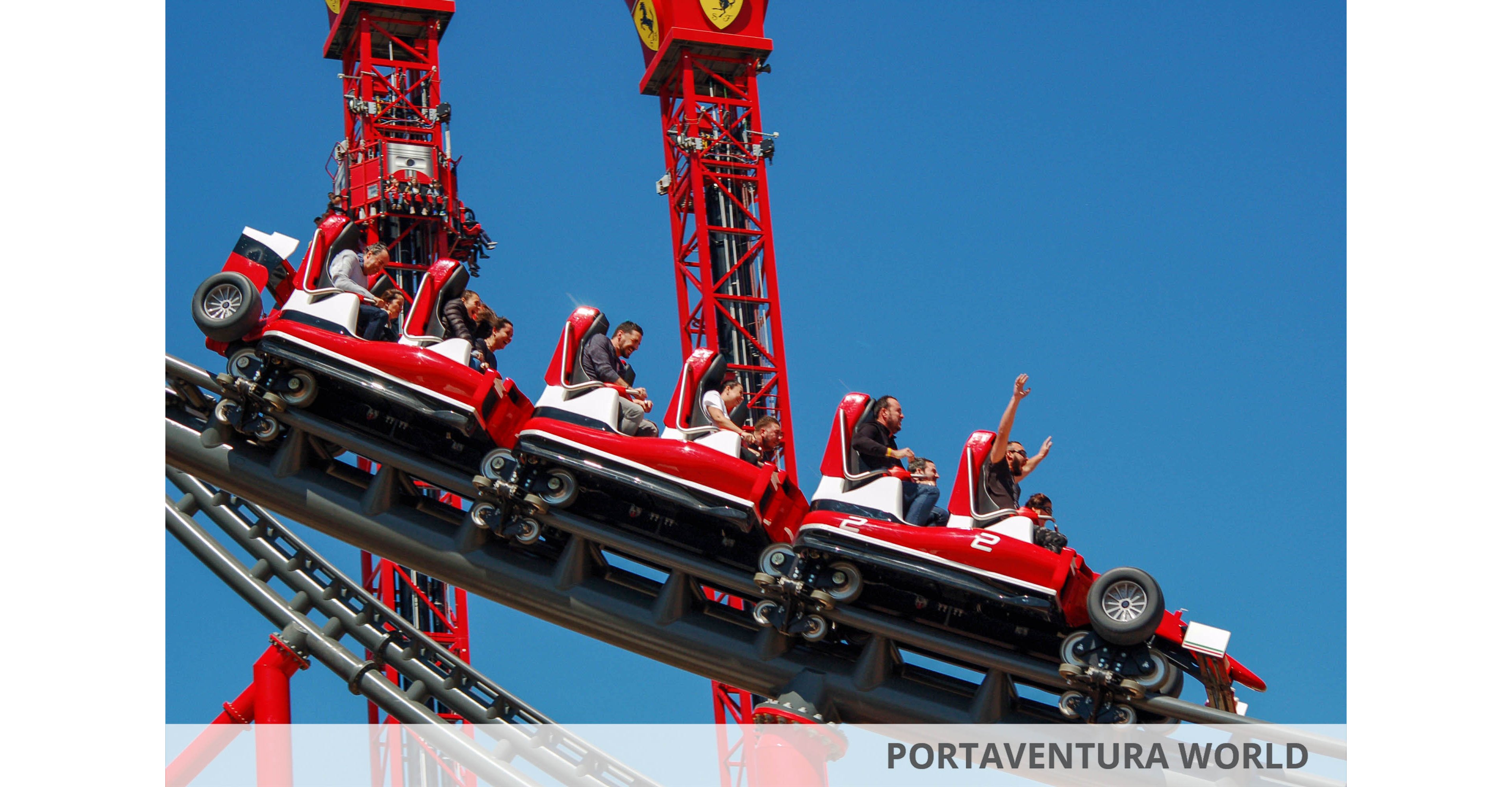 A group of people enjoy a thrilling ride on a red roller coaster under a clear blue sky. The roller coaster cars are designed to resemble race cars, with visible numbers such as '2' on the side. Riders display excitement and joy, with some raising their hands. The setting is an amusement park, and the overall mood is energetic and adventurous.