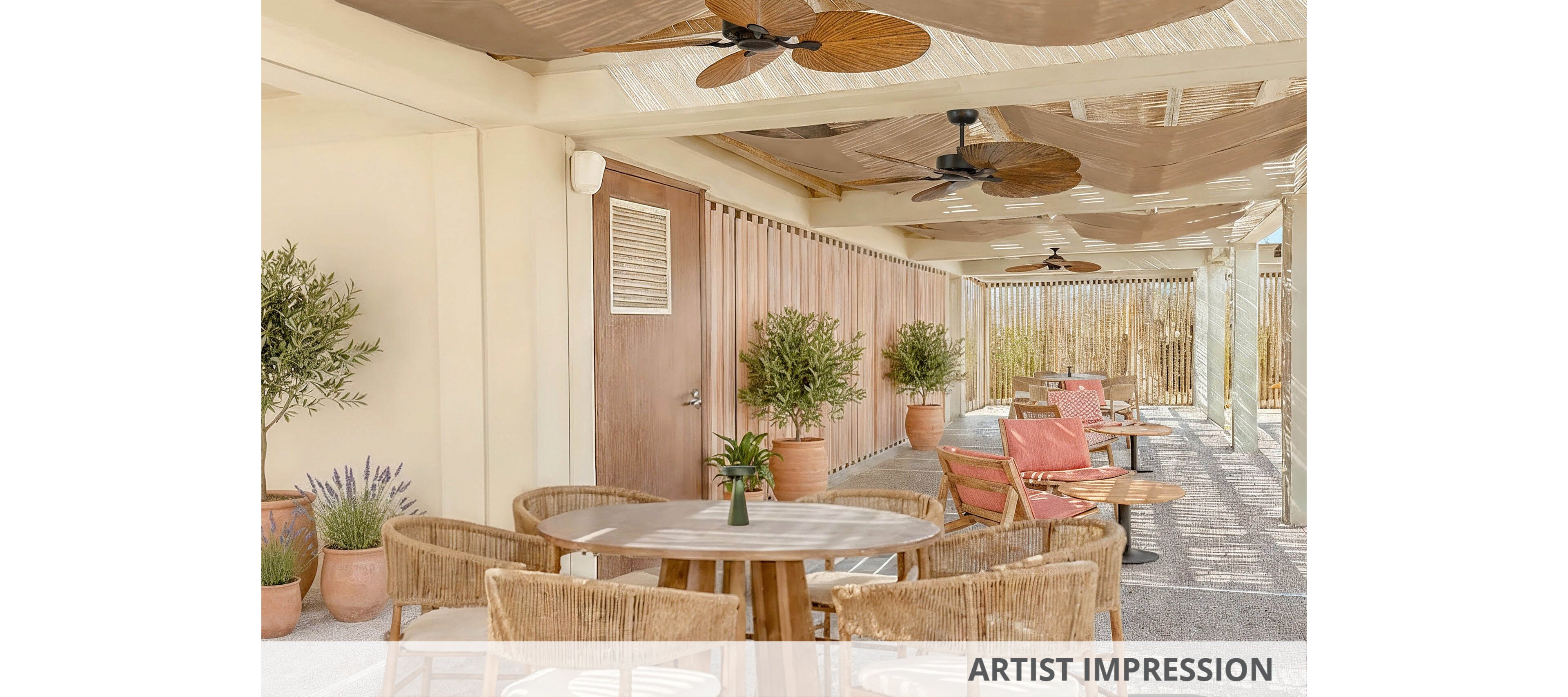 An inviting outdoor patio features round wooden tables surrounded by wicker chairs. The setting appears to be a café or lounge area with neutral-toned walls and a wooden door. Potted plants and greenery line the space, adding a natural touch. Overhead, woven shades and ceiling fans create a relaxed, breezy atmosphere with soft, warm lighting.