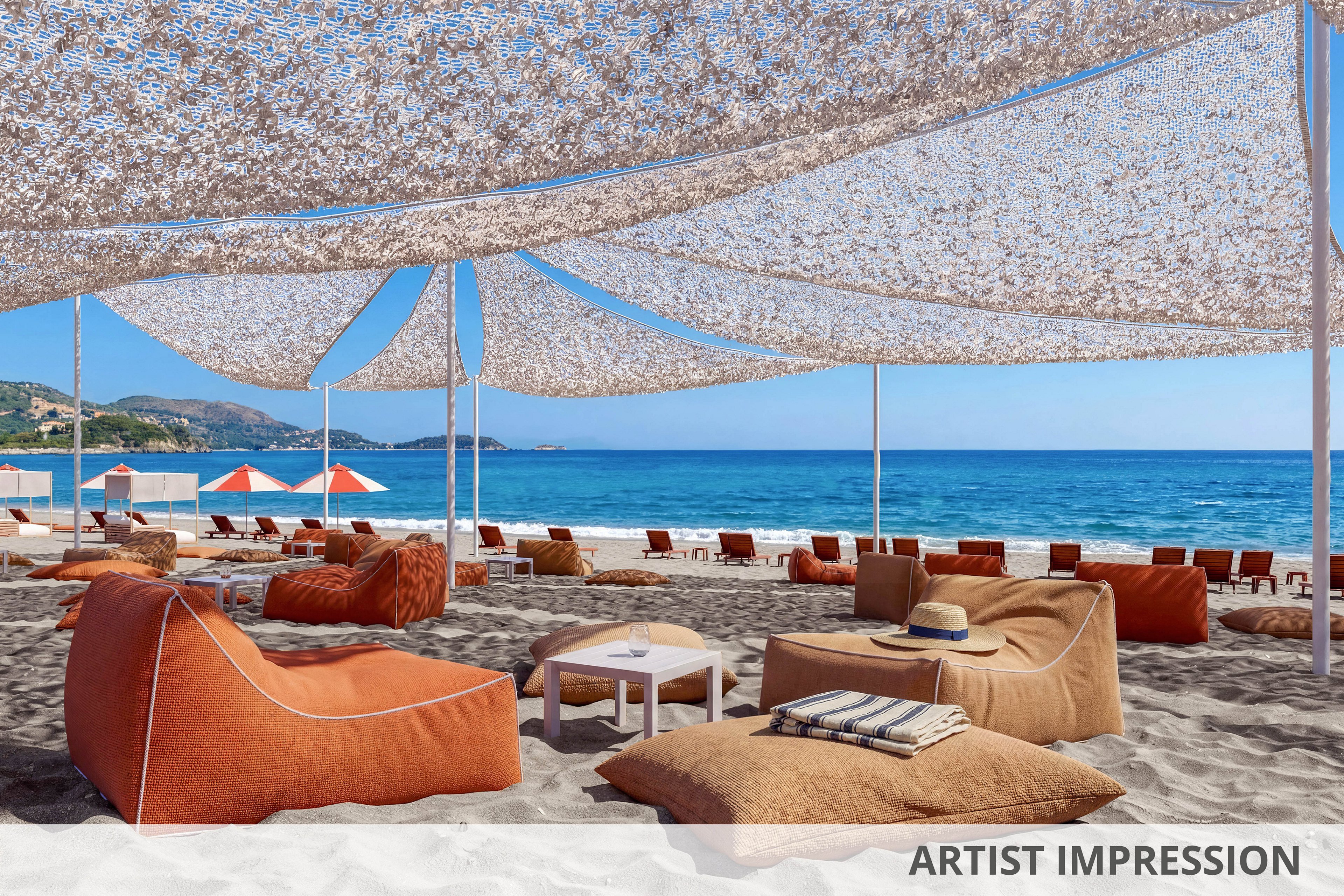 A stylish beach lounge area is set up on soft sand beneath large woven shade canopies. Comfortable orange lounge chairs and cushions surround low tables, with a straw hat resting on one of the seats. In the background, rows of matching orange umbrellas line the shoreline beside the calm blue sea. Distant hills and a clear sky complete the serene coastal setting, suggesting a relaxed vacation atmosphere.