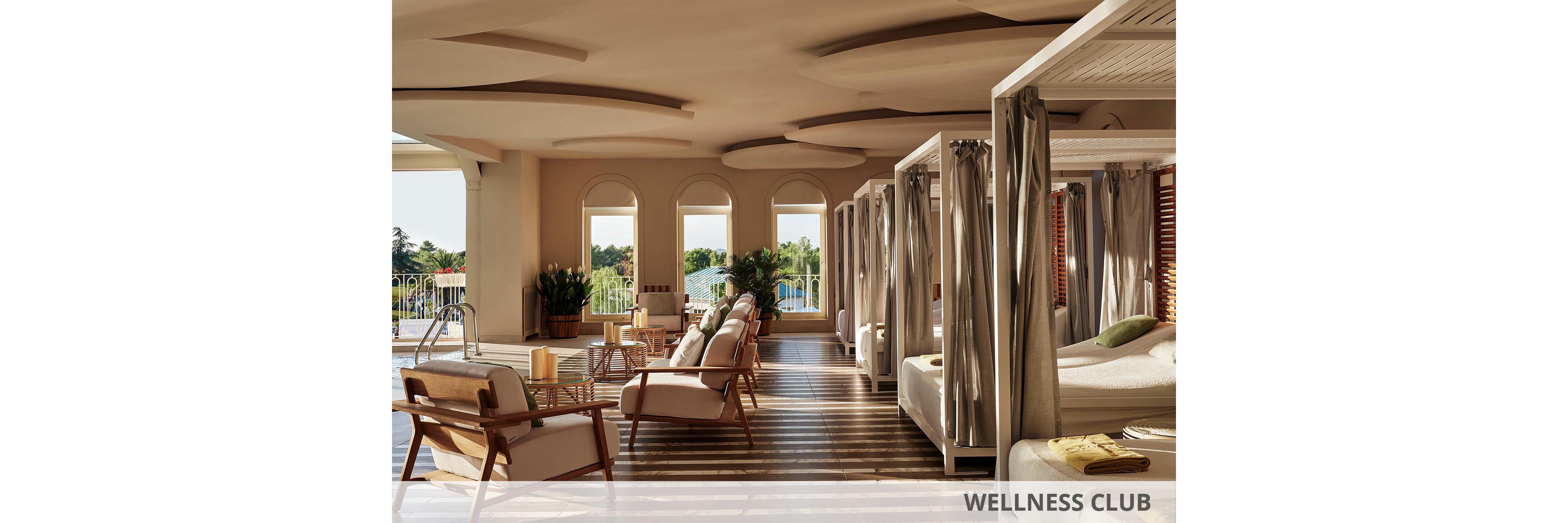 A serene indoor lounge area features cushioned lounge chairs and canopy daybeds arranged beside large arched windows. Soft natural light streams in, casting patterned shadows across the striped floor. Neutral beige and cream tones dominate the space, accented by wooden furniture and green potted plants. The scene suggests a tranquil spa or resort environment designed for relaxation and comfort.