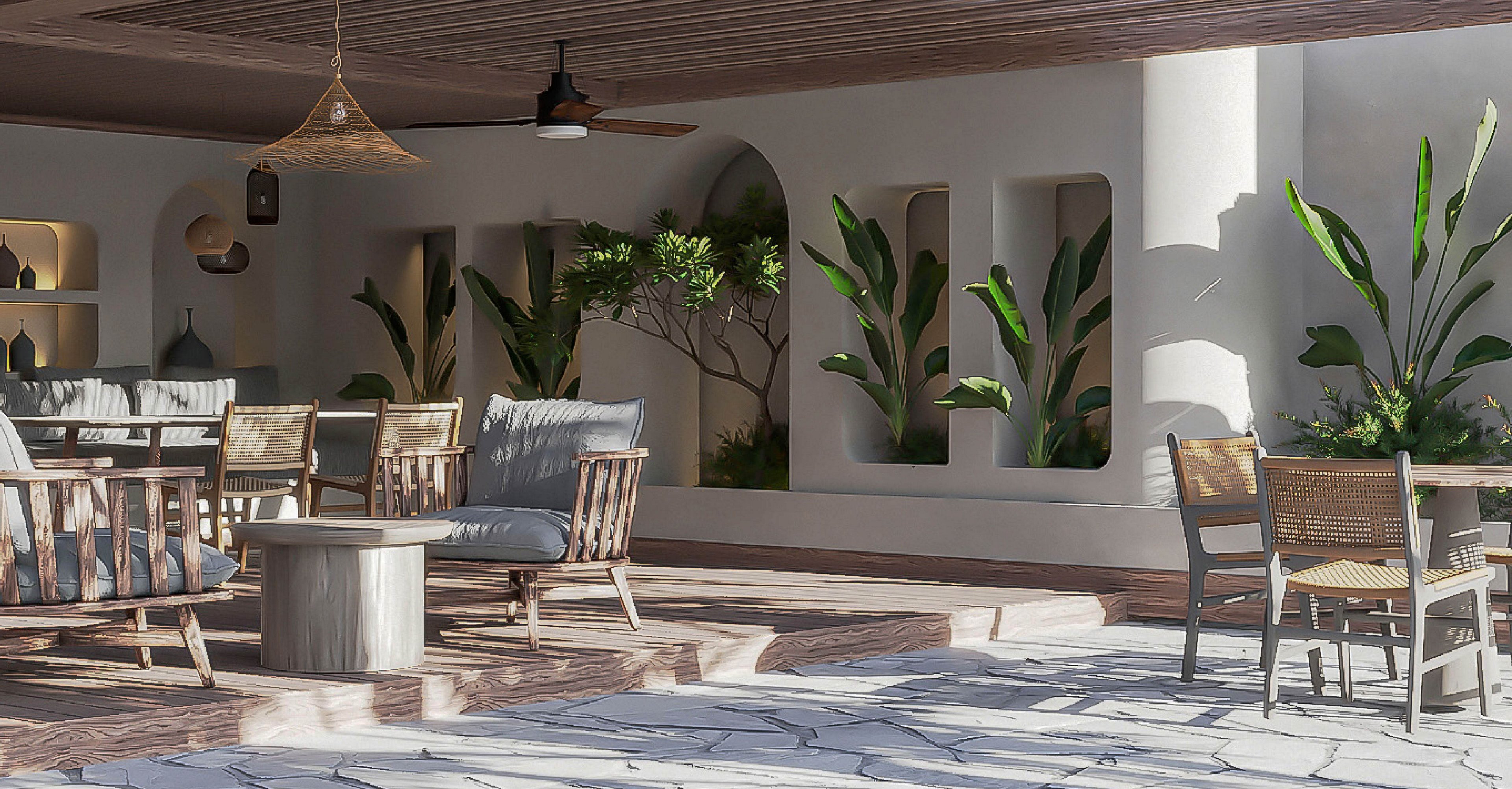 A contemporary open-air lounge features wooden chairs and cushioned armchairs arranged around small tables. Sunlight streams across a stone-tiled floor, creating bright patterns and a relaxed atmosphere. Built-in wall niches and arches showcase potted green plants, adding natural accents to the neutral decor. The space combines modern design with warm, earthy materials for a tranquil social setting.