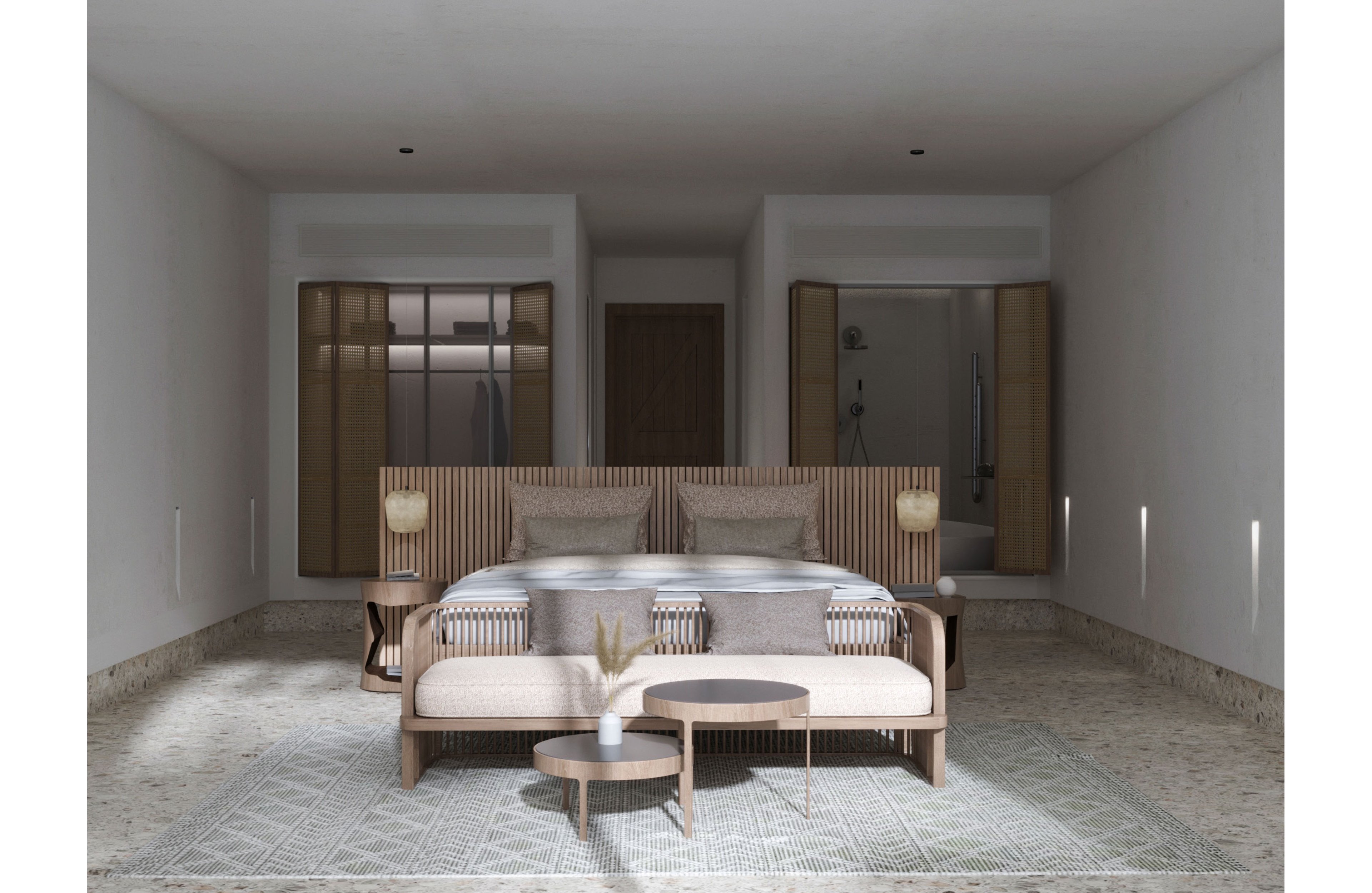 A contemporary bedroom features a large bed with neutral bedding and a wooden slatted headboard. Matching bedside tables with warm lamps flank the bed, while a cushioned bench and small round tables sit at the foot. Built-in closets and an open doorway to a bathroom are visible in the background, enhancing the sense of depth. Soft natural light and a patterned area rug contribute to the calm, minimalist atmosphere.