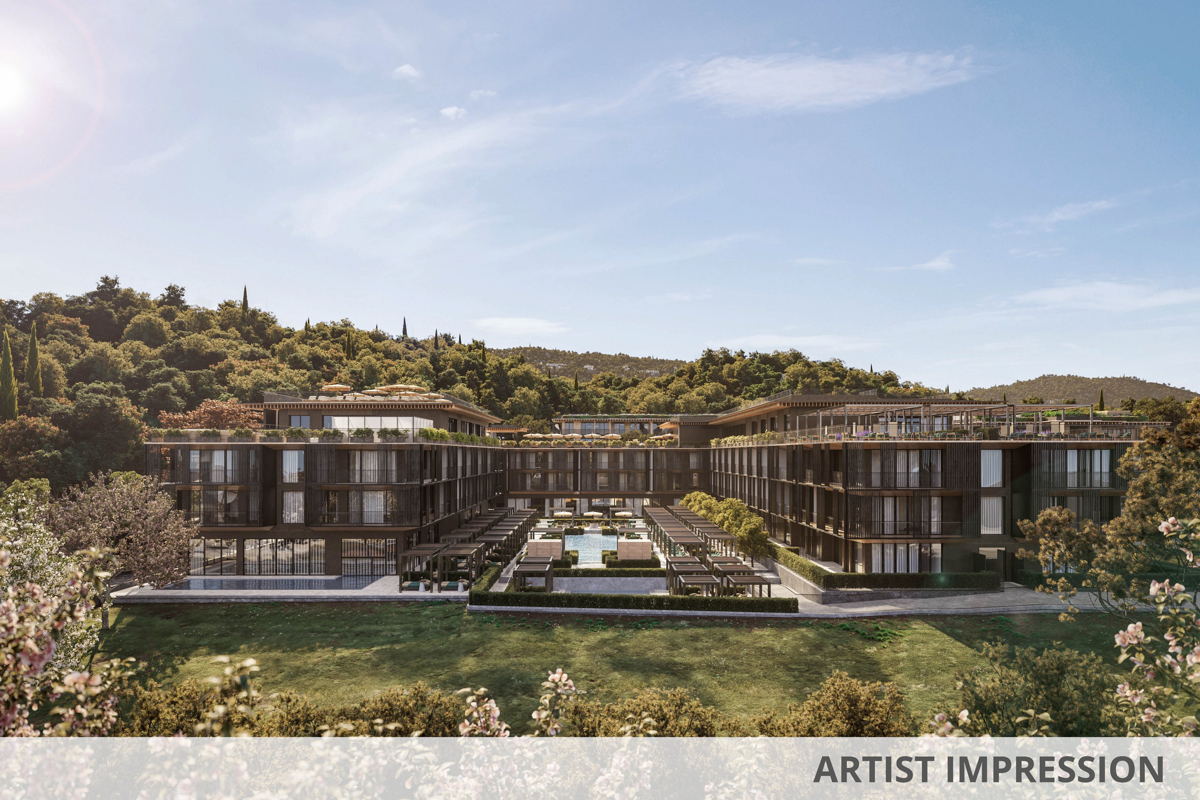 A contemporary hotel complex is set against a lush, green hillside under a clear blue sky. The building features sleek, dark facades and expansive glass windows, with a central courtyard that includes a swimming pool and landscaped gardens. The tranquil setting and modern architecture evoke a sense of relaxation and exclusivity. No visible text or numbers are present in the image.